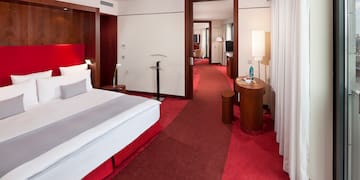 a hotel room with red carpet and white bed