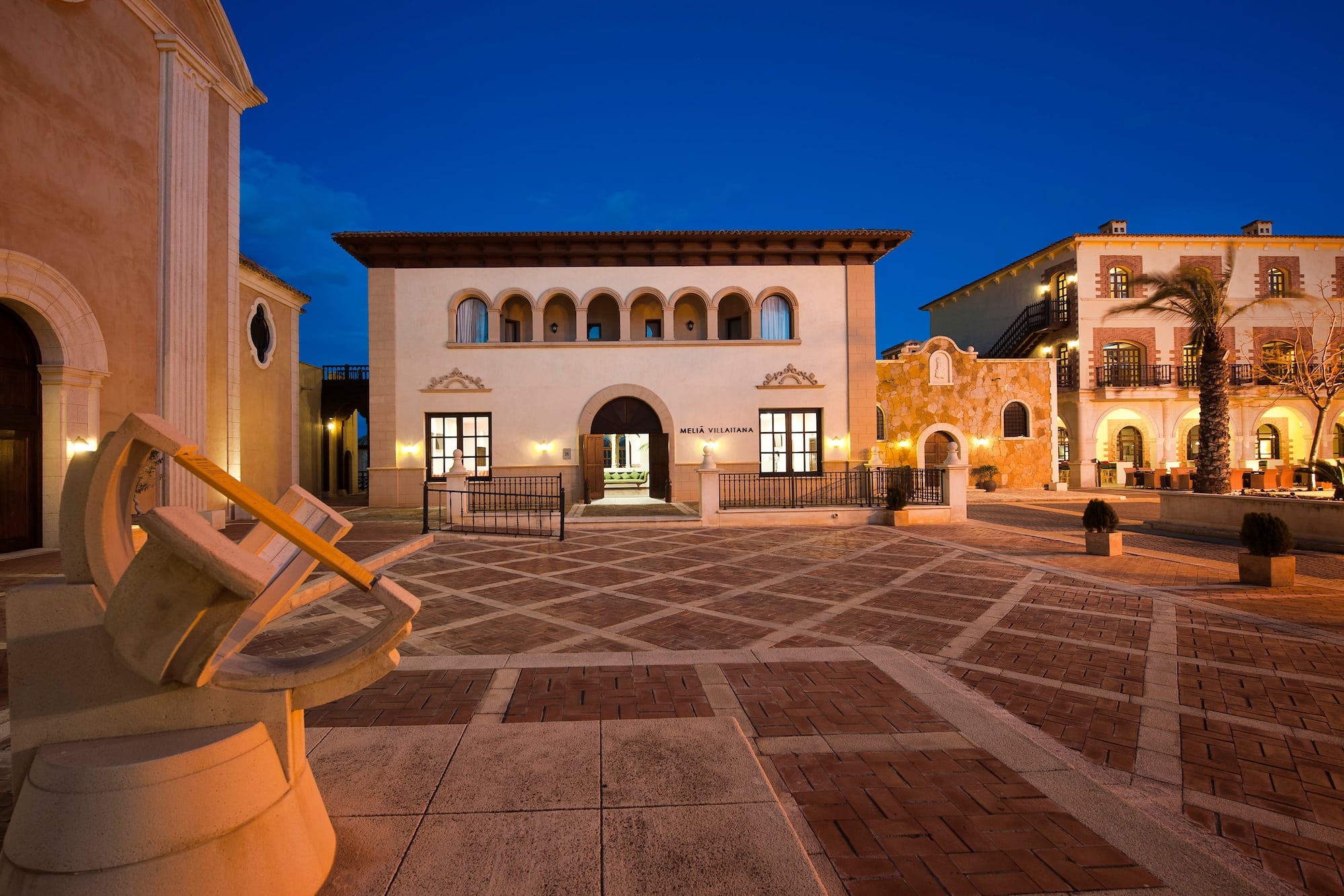 Melia Villaitana resort exterior at dusk, showcasing Spanish architecture and plaza.