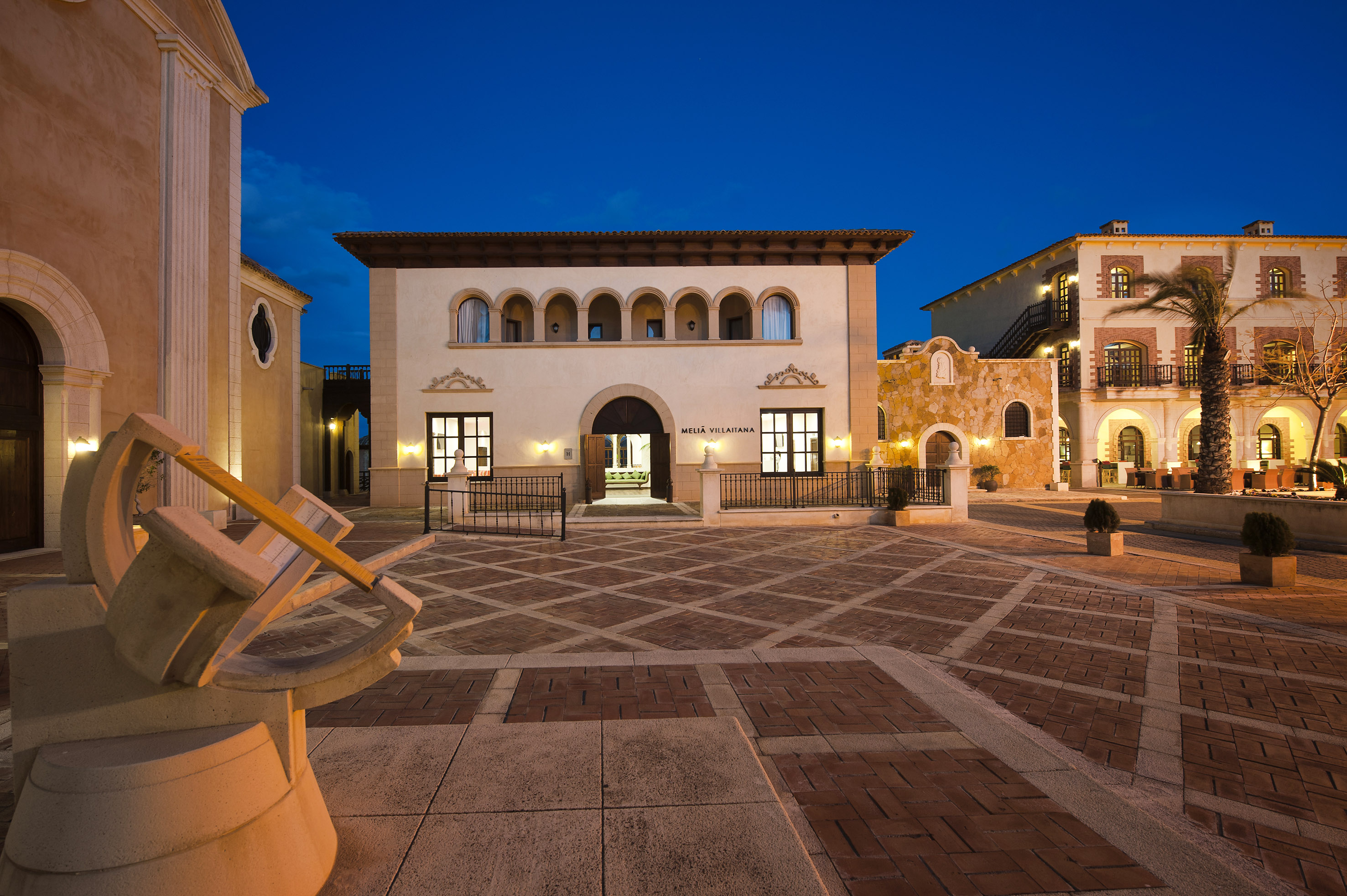 Melia Villaitana resort exterior at dusk, showcasing Spanish architecture and plaza.