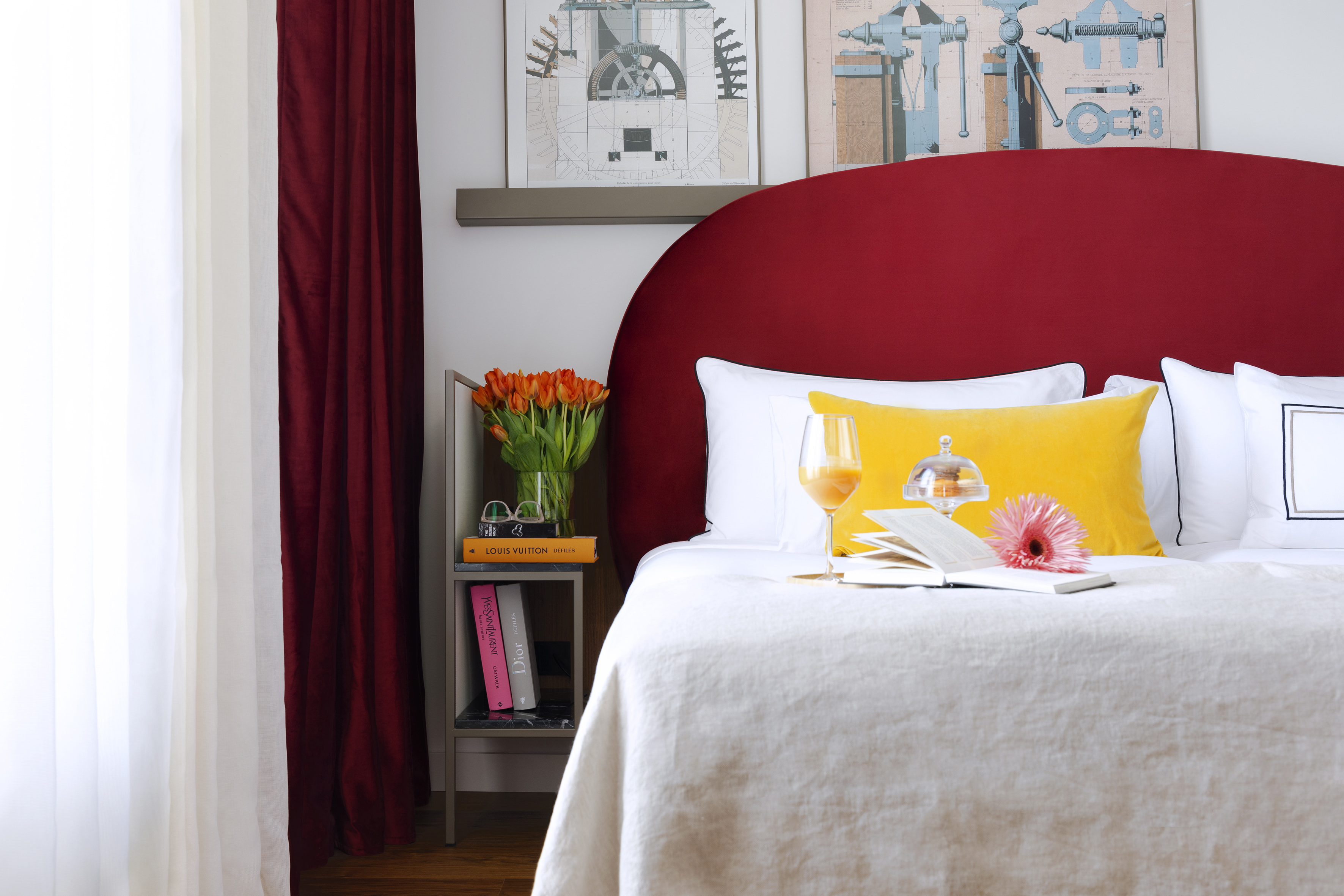 Bedroom with red headboard, white bed, yellow pillow, and orange tulips.