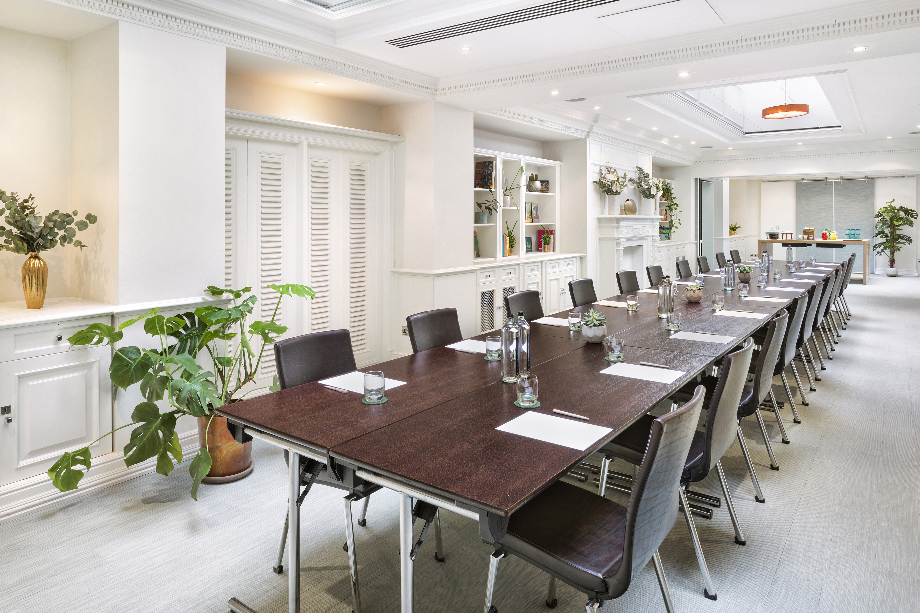 Elegant modern conference room with long table, leather chairs, and lush plants.