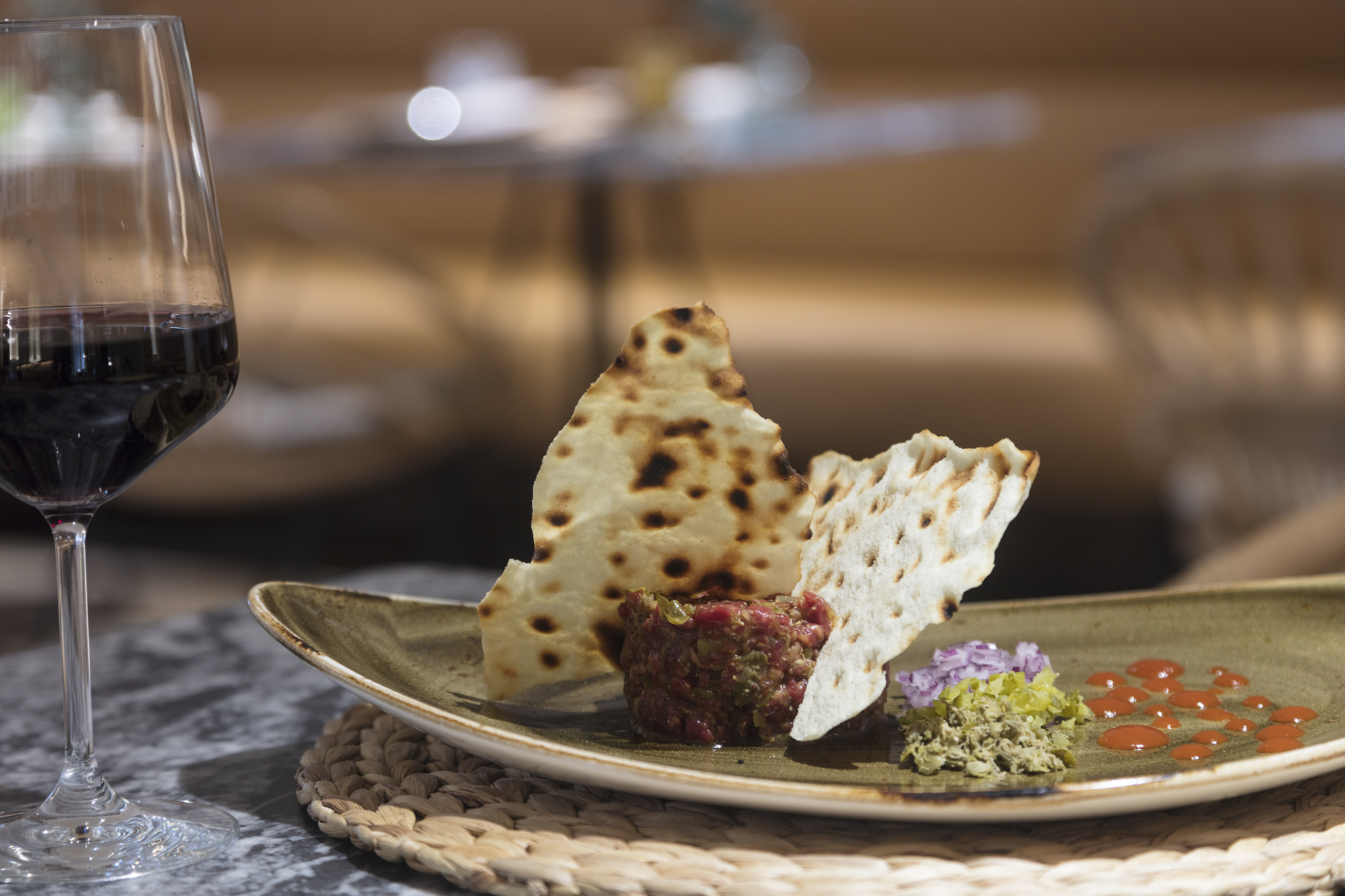 Gourmet steak tartare, crispy flatbread, red onion, relish, and red wine.