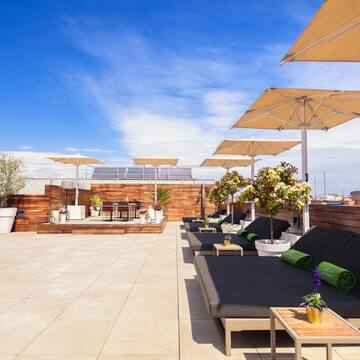 a deck with lounge chairs and umbrellas on a rooftop
