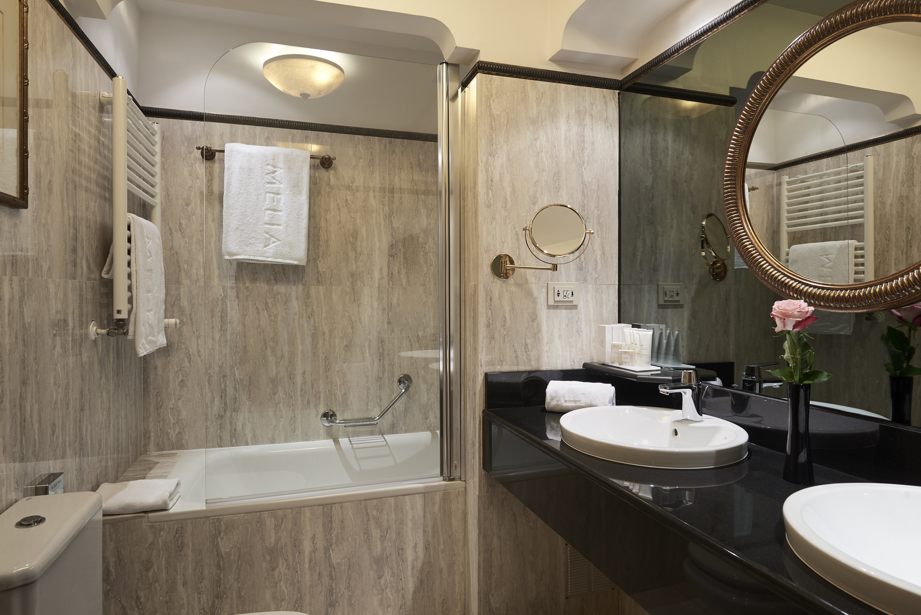 Melia hotel bathroom: tiled walls, bathtub, double vanity, oval mirror.
