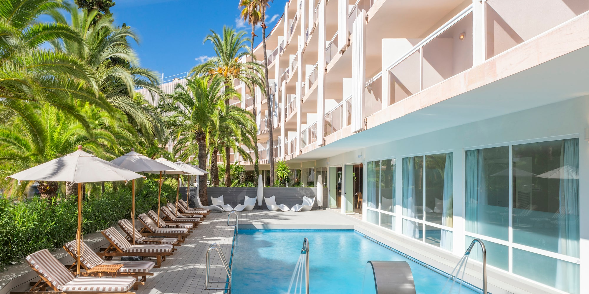 a pool with lounge chairs and umbrellas in front of a building
