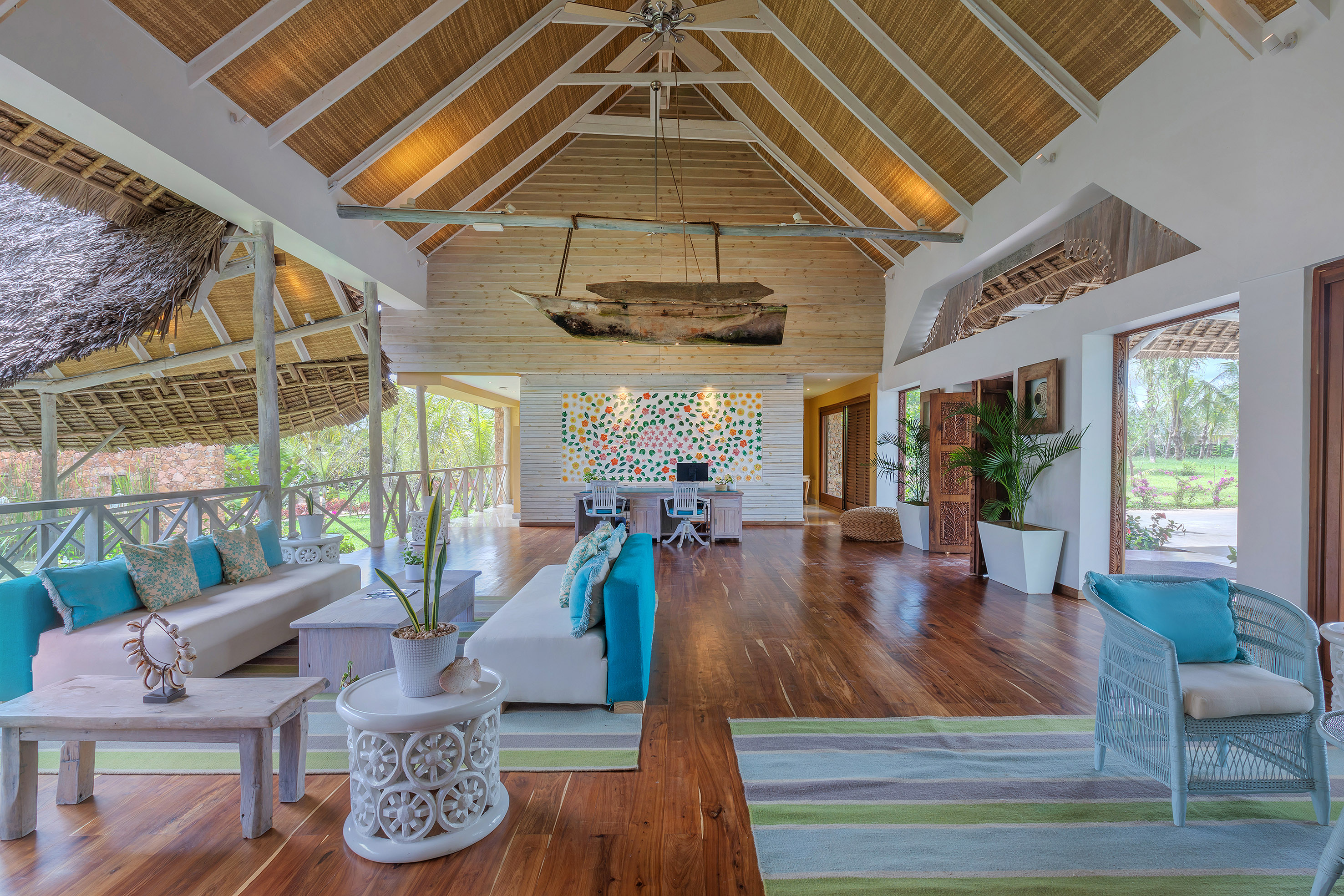 Tropical resort lobby with thatched roof, wooden boat decor, and reception area.
