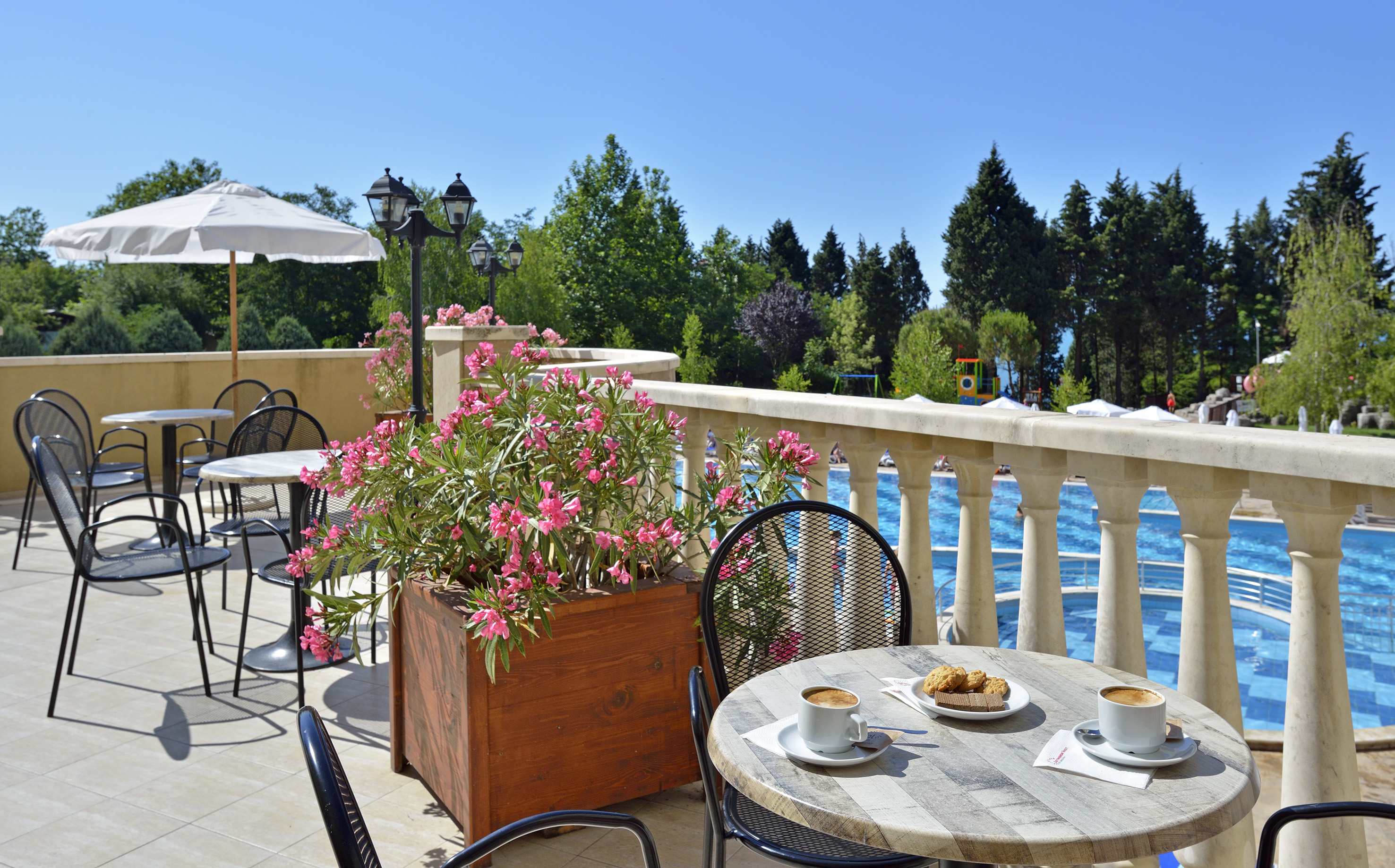 a table and chairs on a patio with a view of water and trees