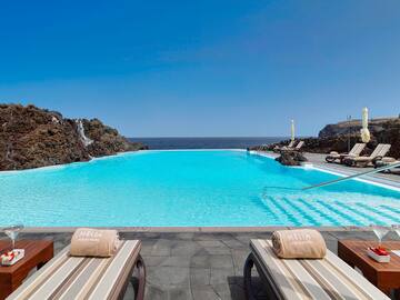 a pool with chairs and rocks in the background