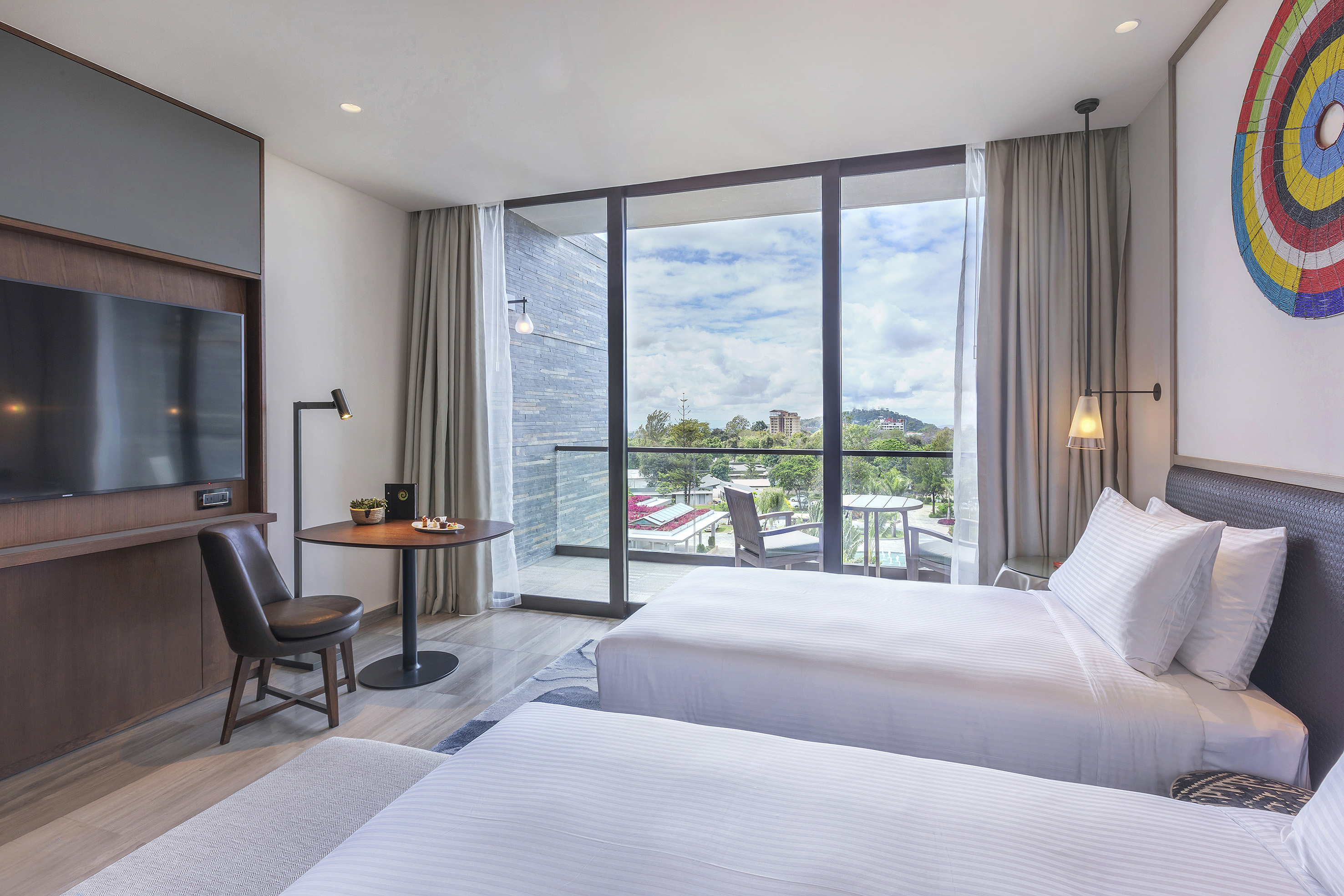 Modern hotel room with two twin beds, balcony city view.