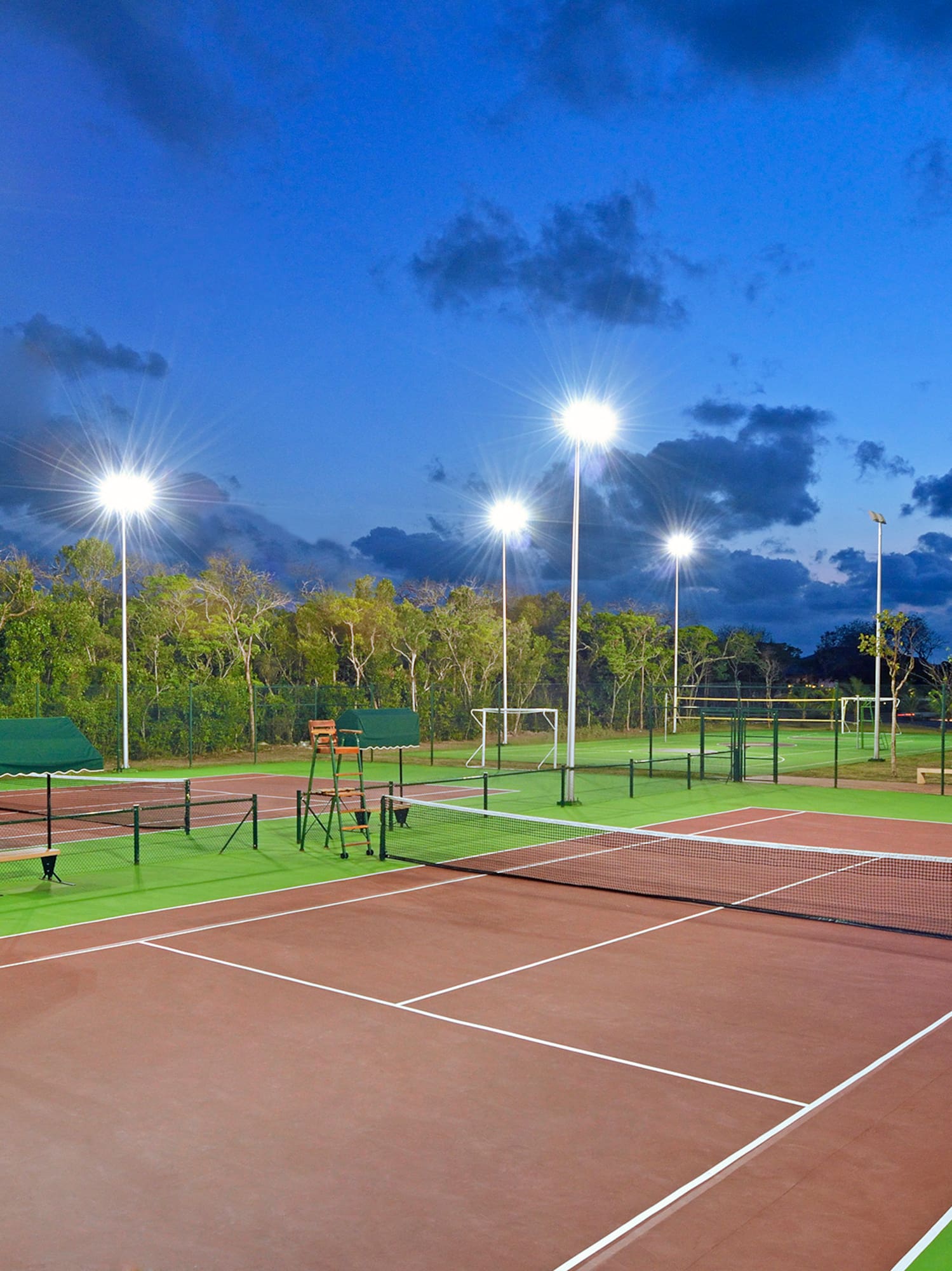 a tennis court with lights and trees