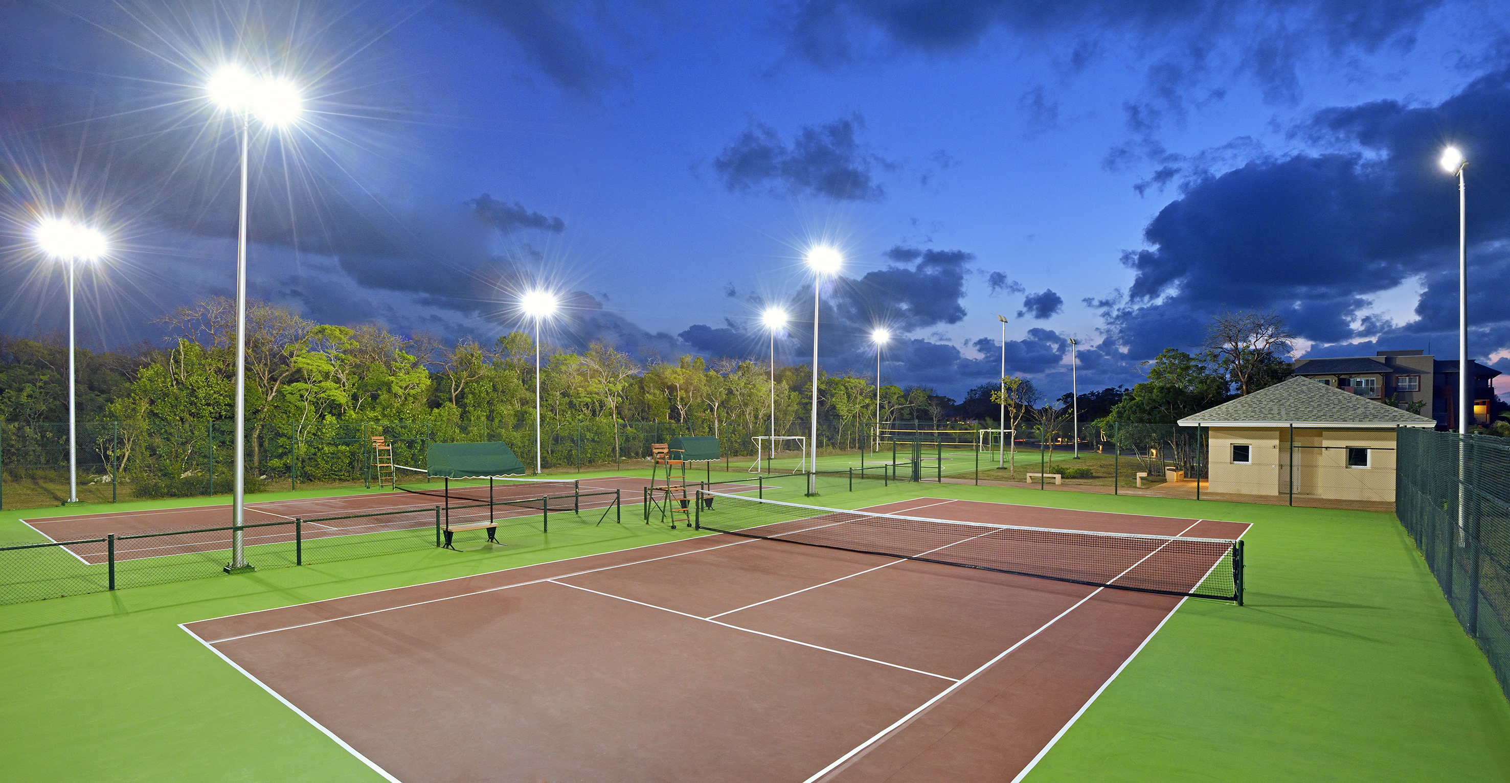 a tennis court with lights and trees