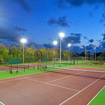 a tennis court with lights and trees