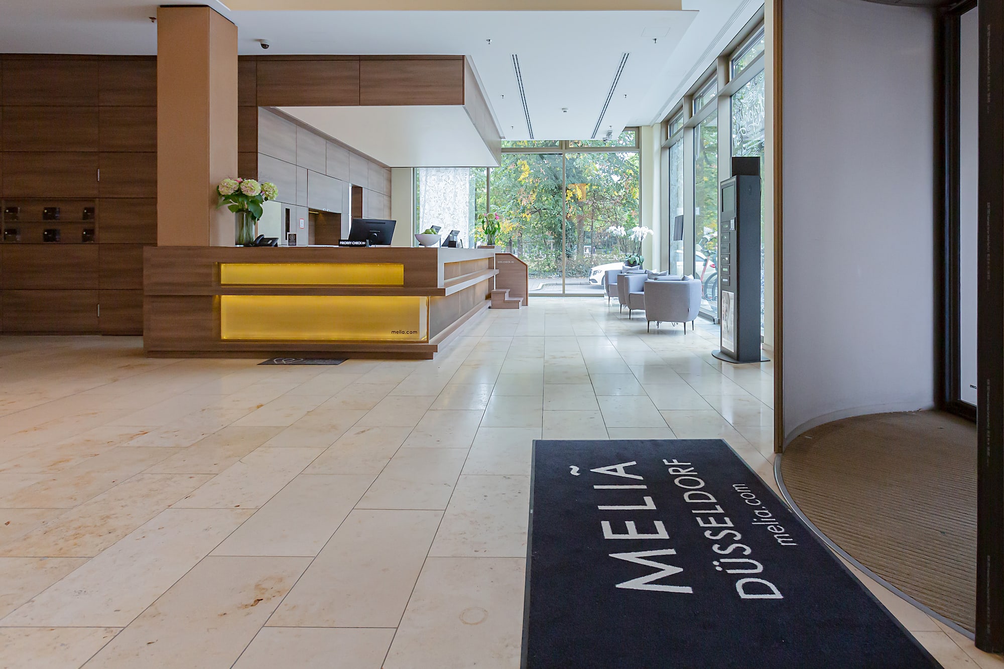 Meliá Düsseldorf hotel lobby, modern reception desk, tiled floor, large windows.