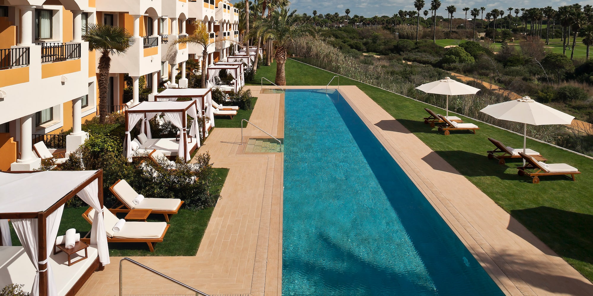 a pool with lounge chairs and umbrellas in front of a building