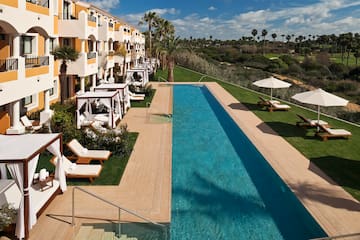a pool with lounge chairs and umbrellas in front of a building