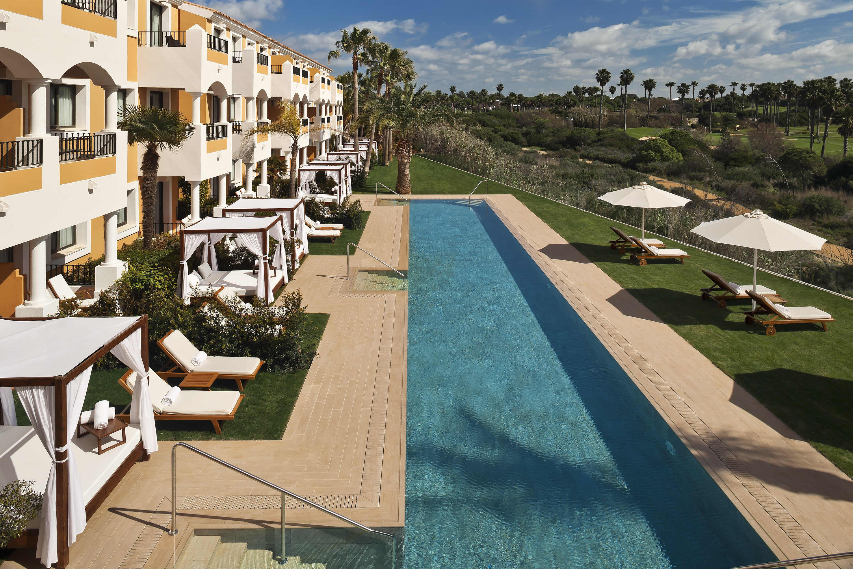 a pool with lounge chairs and umbrellas in front of a building