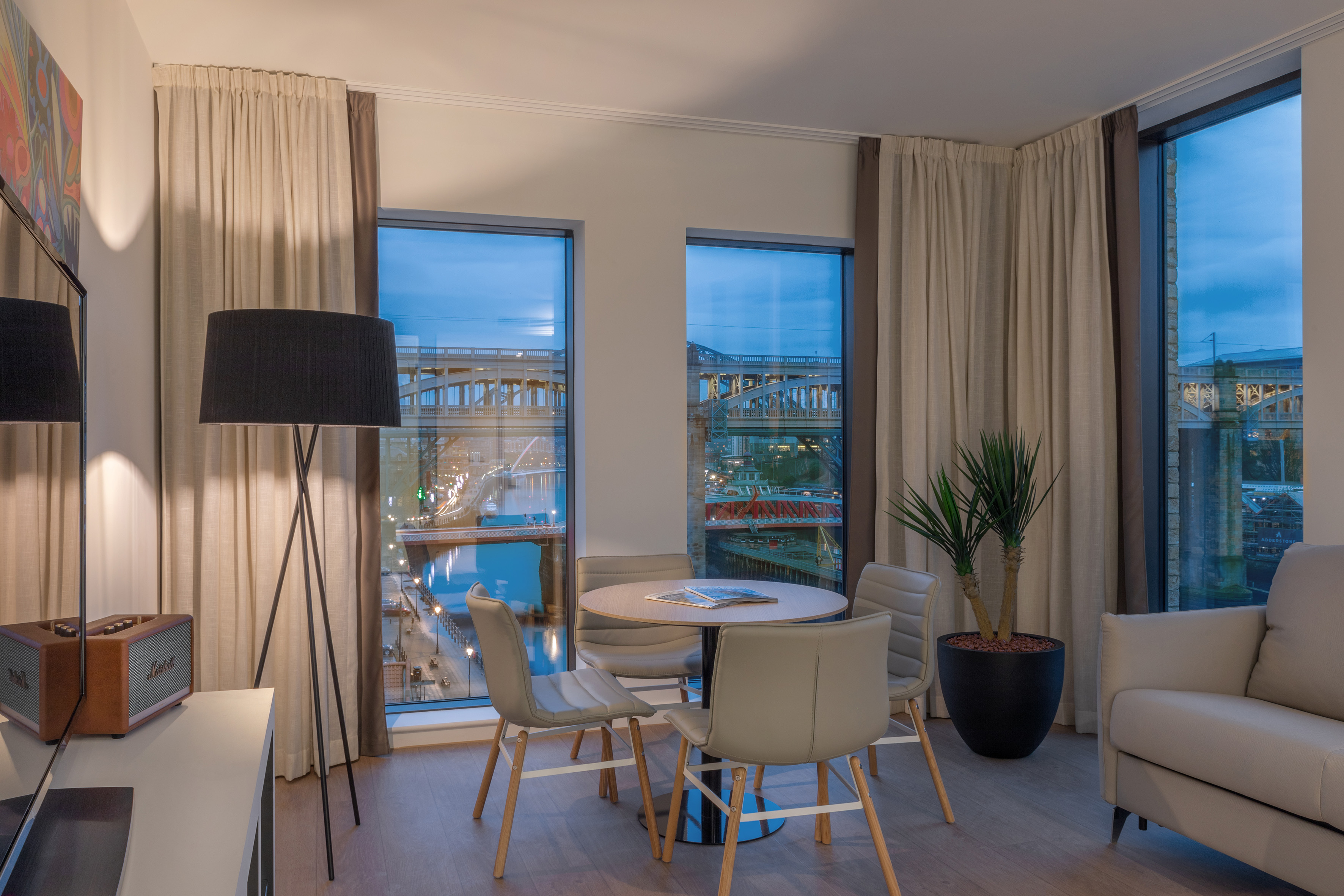 Modern living area with city river view, bridges, dining table, and sofa.