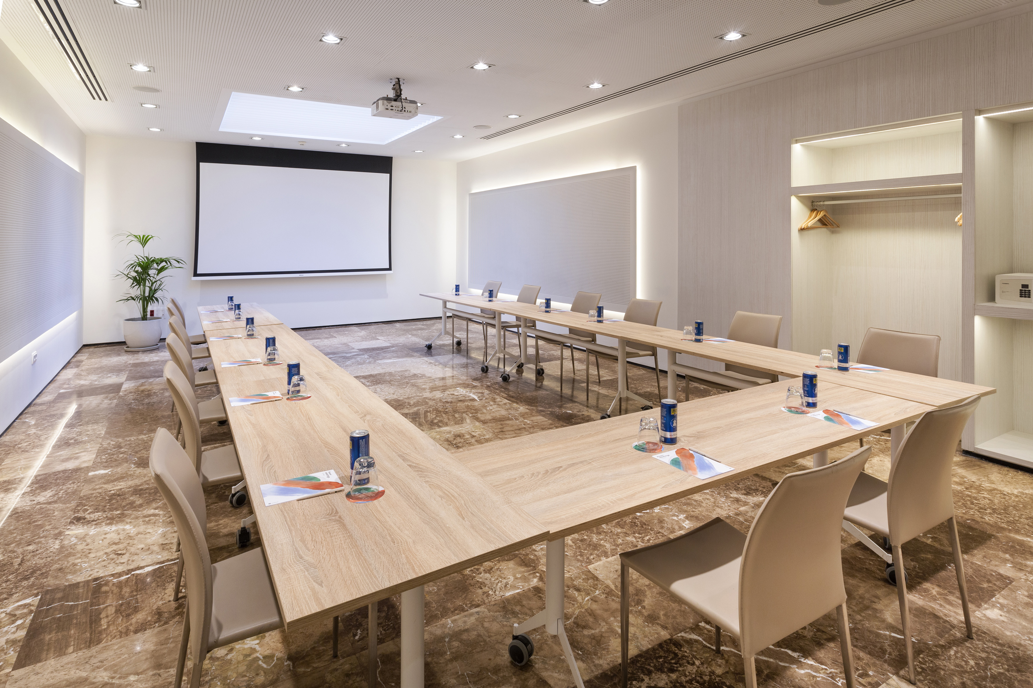 Modern conference room with U-shaped table, projector, and screen.