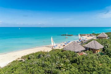 a beach with sailboats and blue water