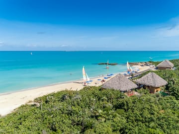 a beach with sailboats and blue water