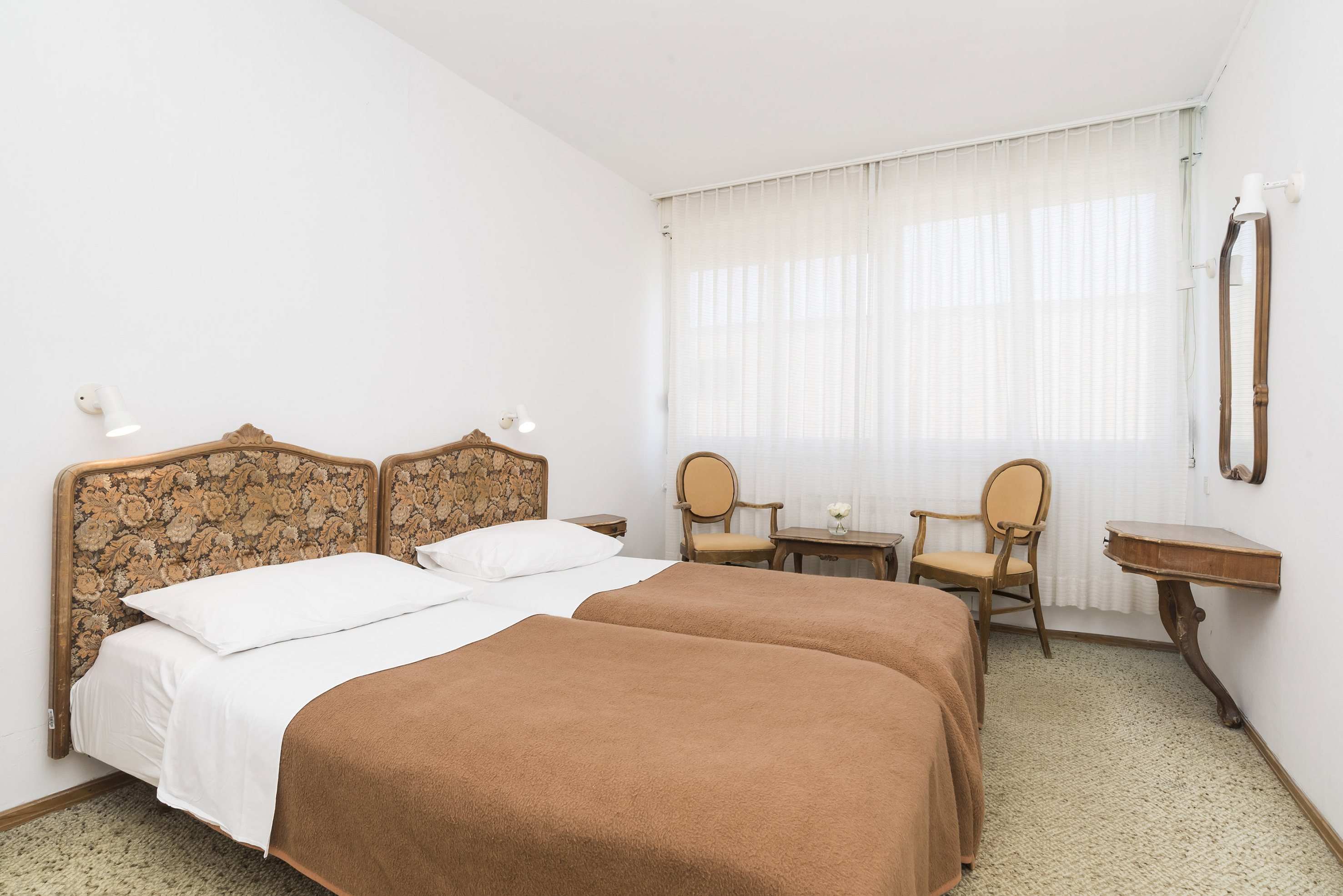 a room with two beds and chairs