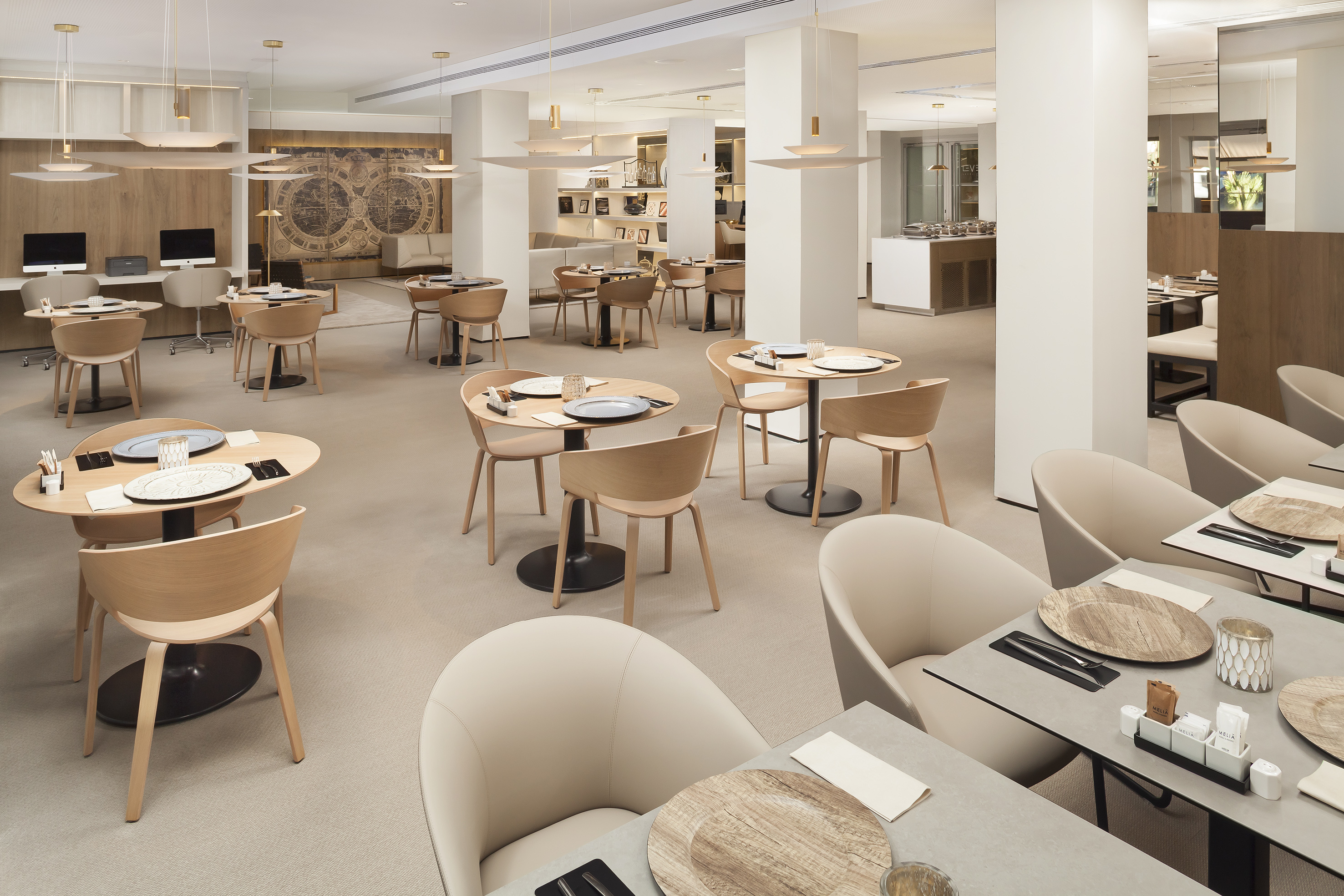 Bright, modern hotel restaurant dining area with wood tables and beige seating.