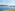 Puerto deportivo mediterráneo con yates, rompeolas de roca y costa urbana.