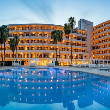 a pool with palm trees and a building with lights