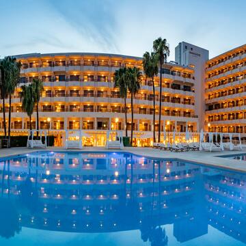 a pool with palm trees and a building with lights