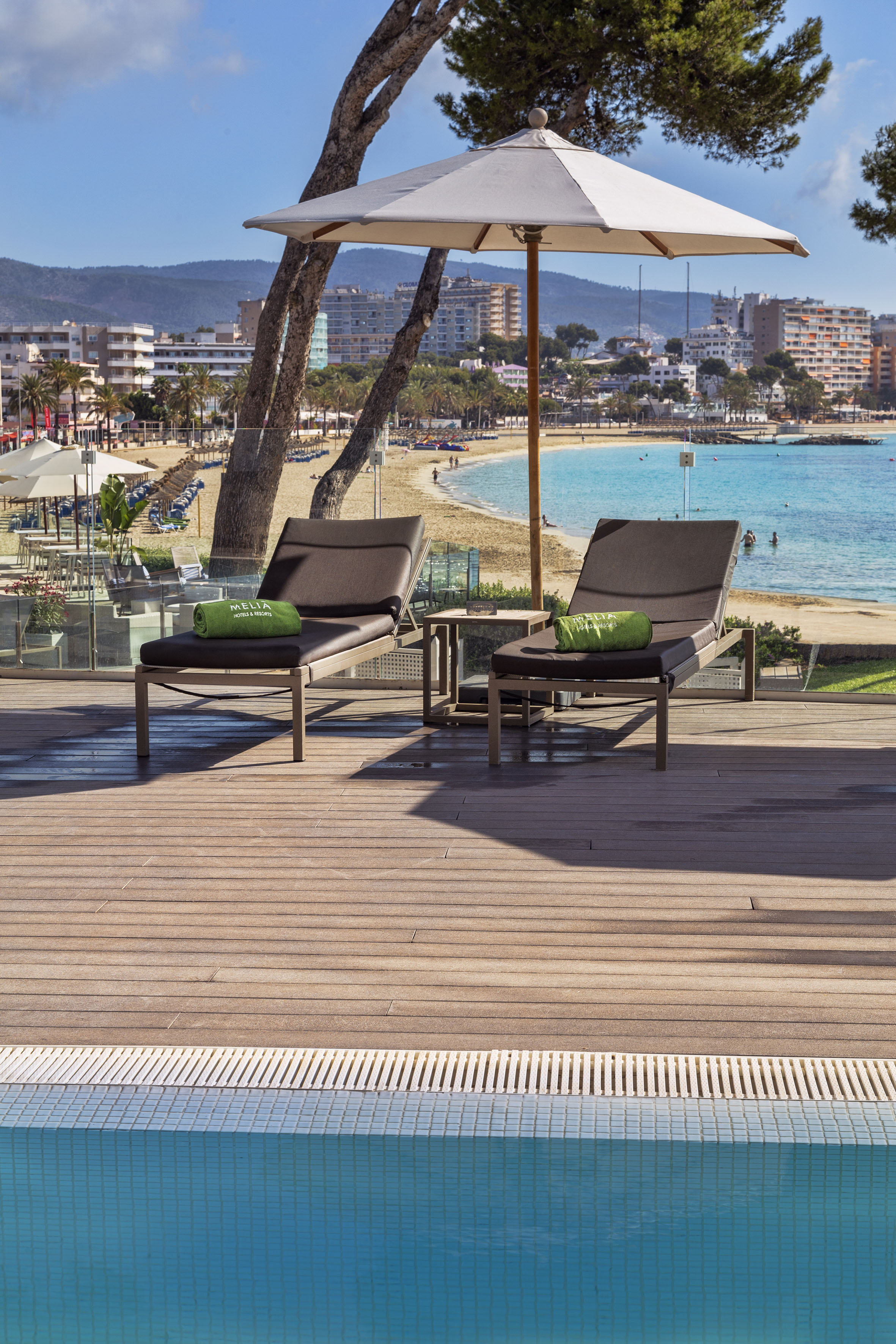 Meliá hotel pool deck with lounge chairs, umbrella, overlooking beach and ocean.