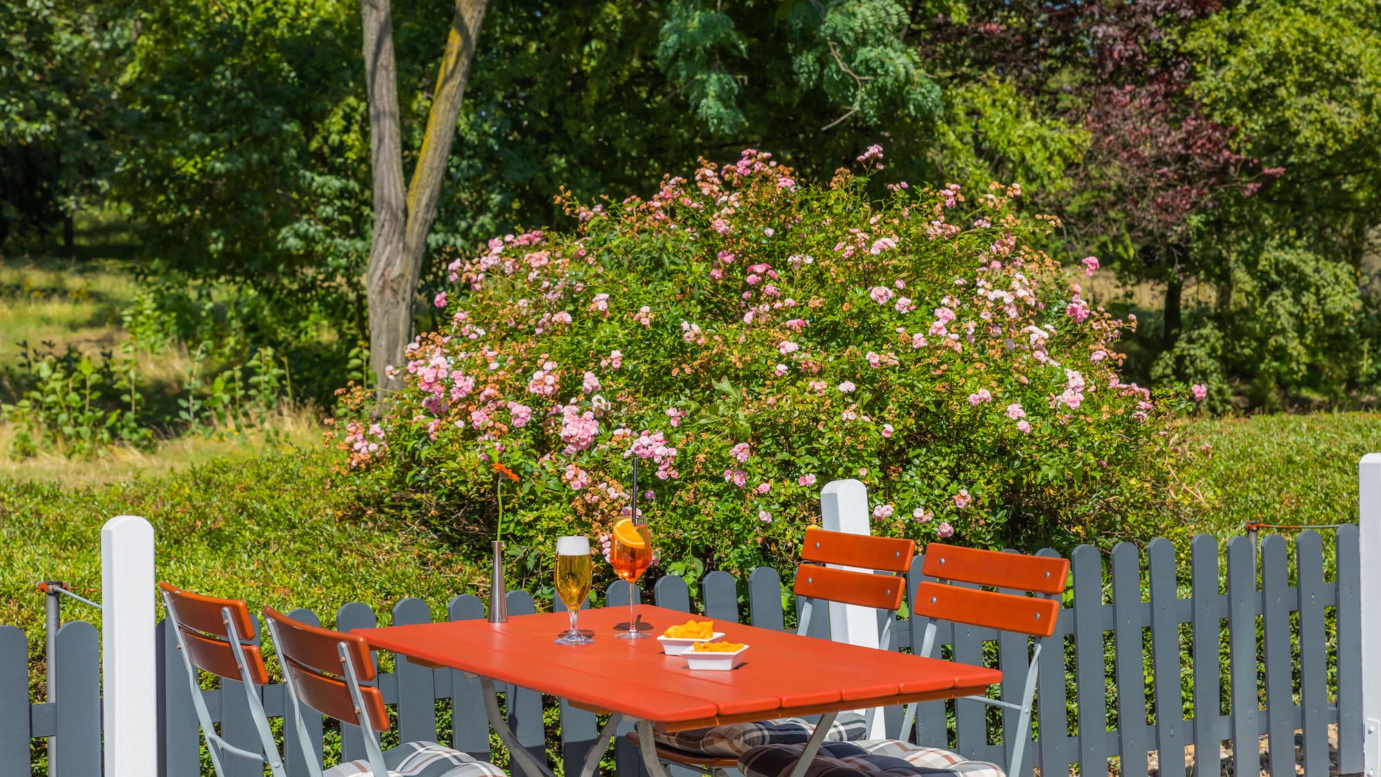 a table and chairs outside with flowers in the background