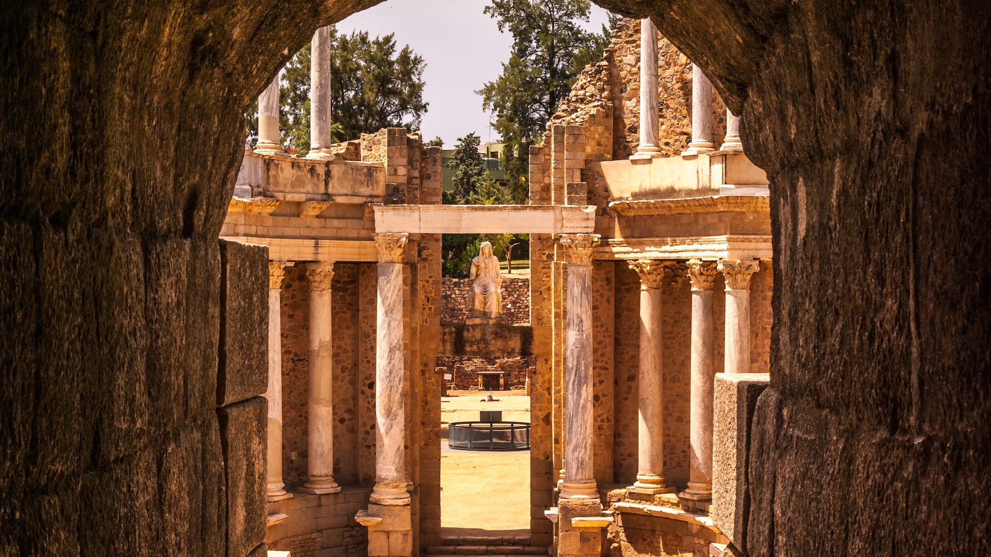 a stone archway with columns and a statue in the background