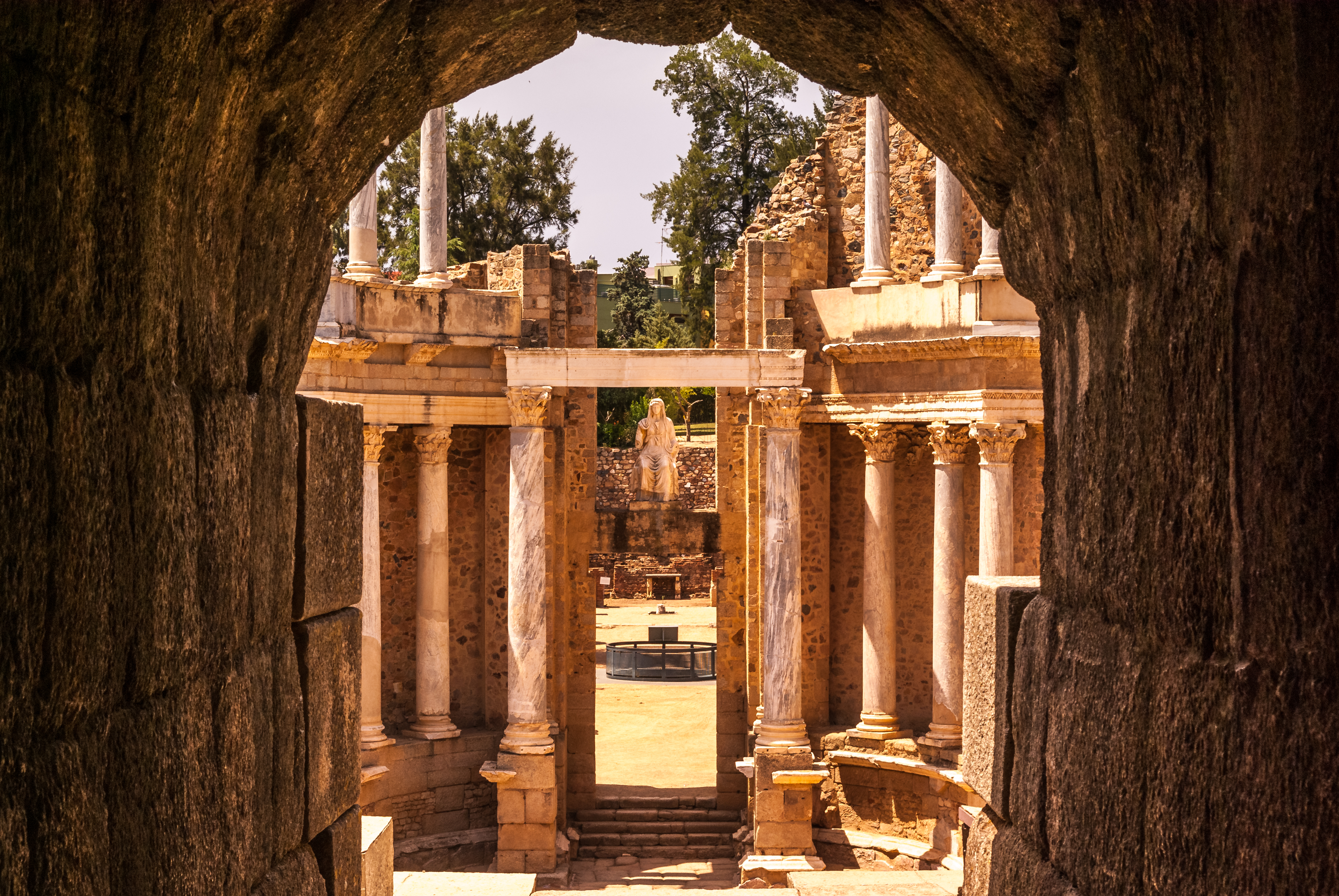 a stone archway with columns and a statue in the background