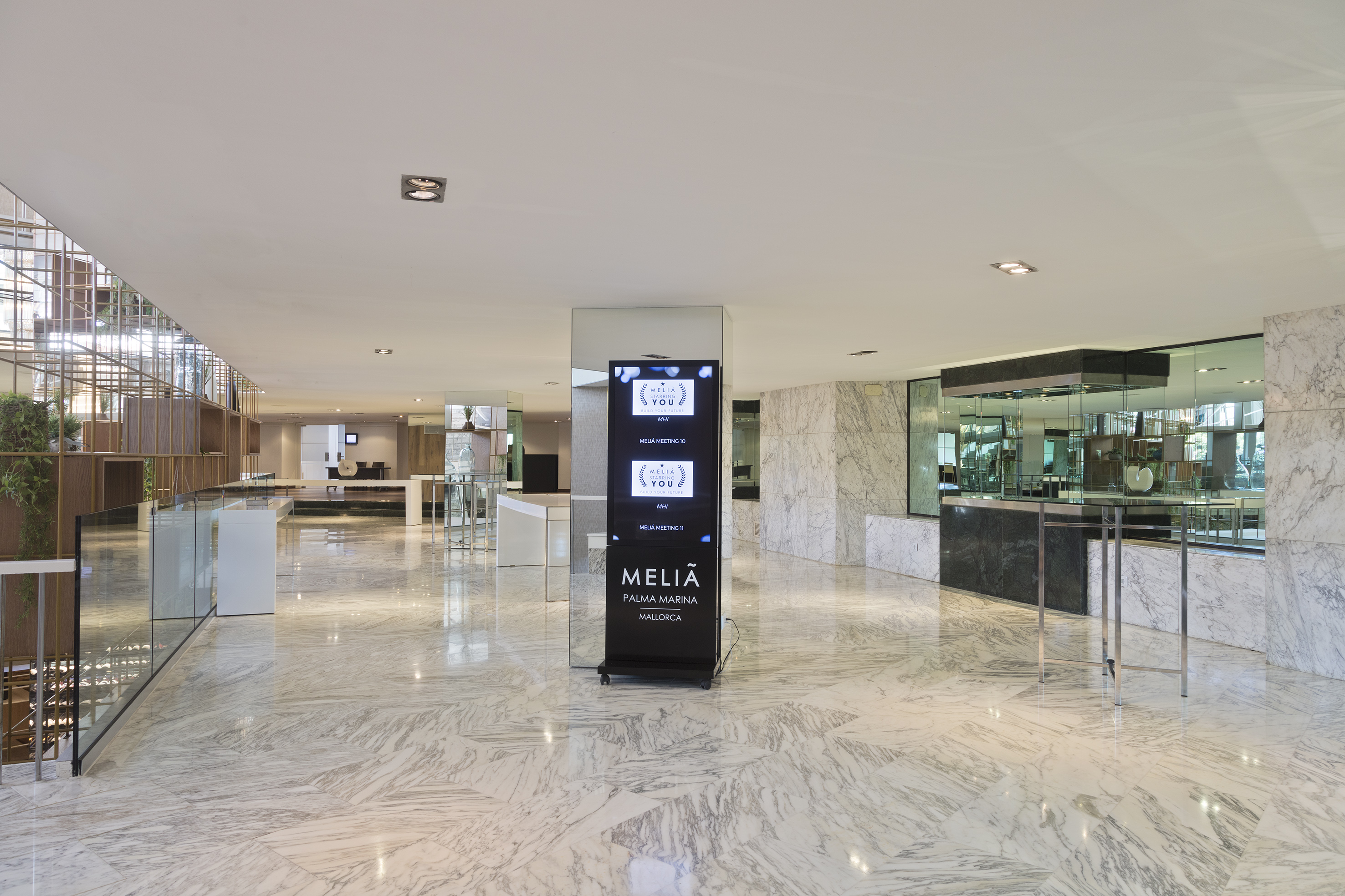 Modern Meliá Palma Marina hotel lobby with marble floors and digital signage.