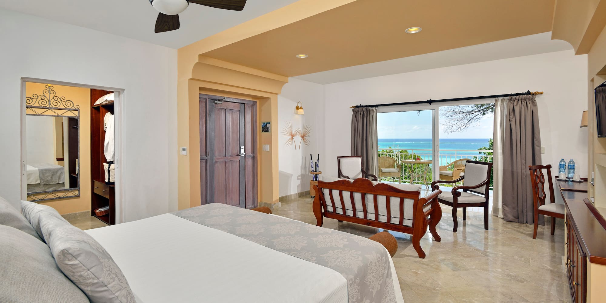 a room with a bed and chairs and a ceiling fan