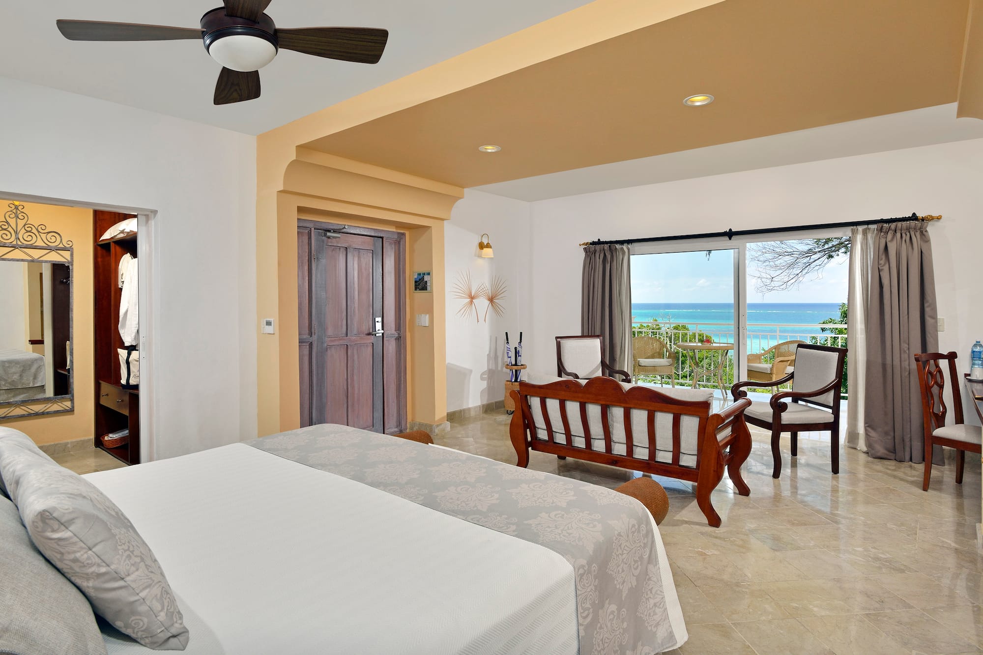 a room with a bed and chairs and a ceiling fan