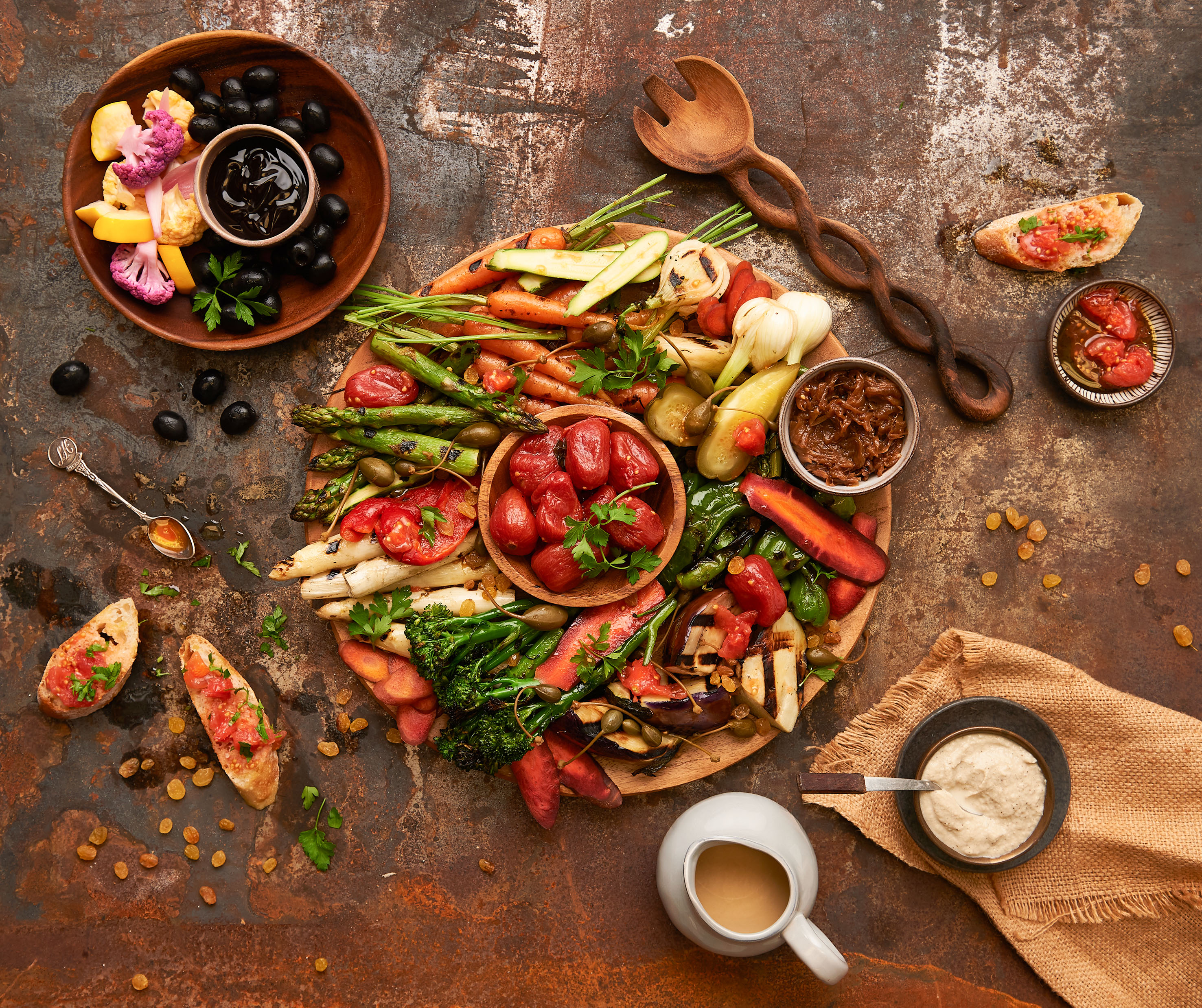 Colorful grilled veggie antipasto platter with dips, olives, and bruschetta.