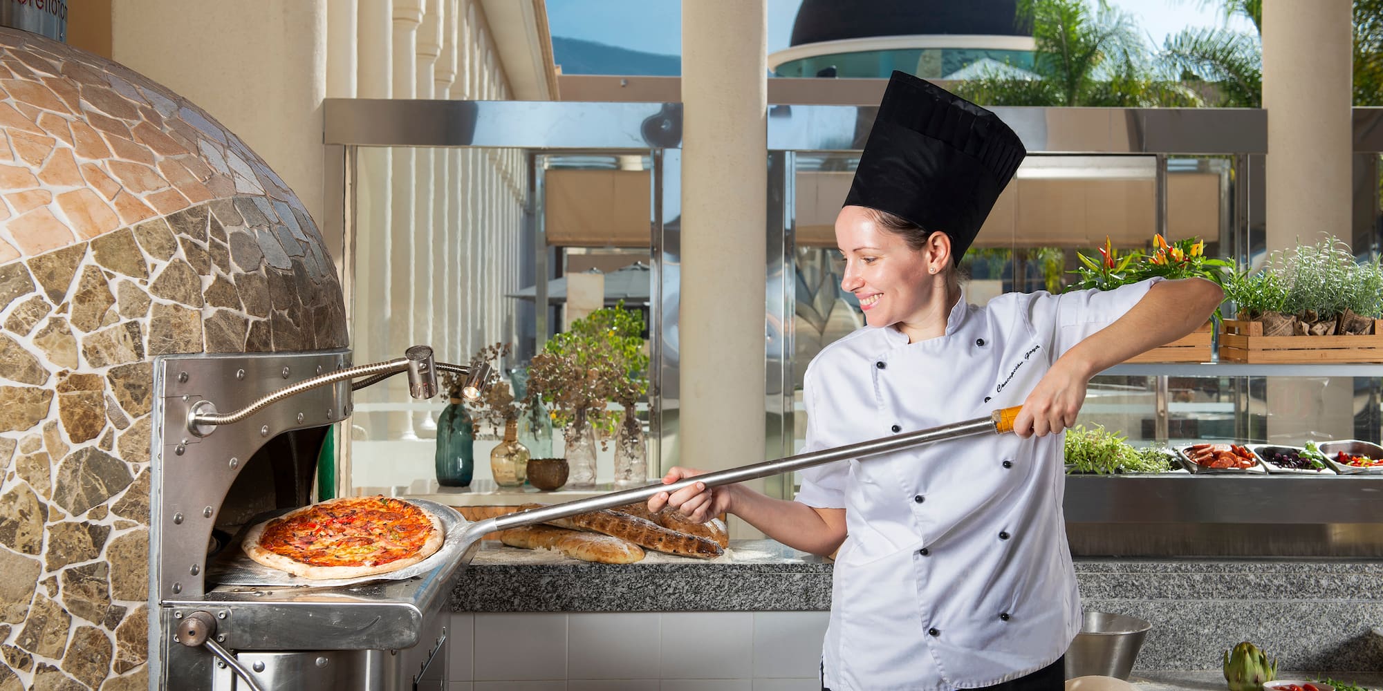 a woman in a chef's uniform making pizza