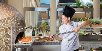 a woman in a chef's uniform making pizza