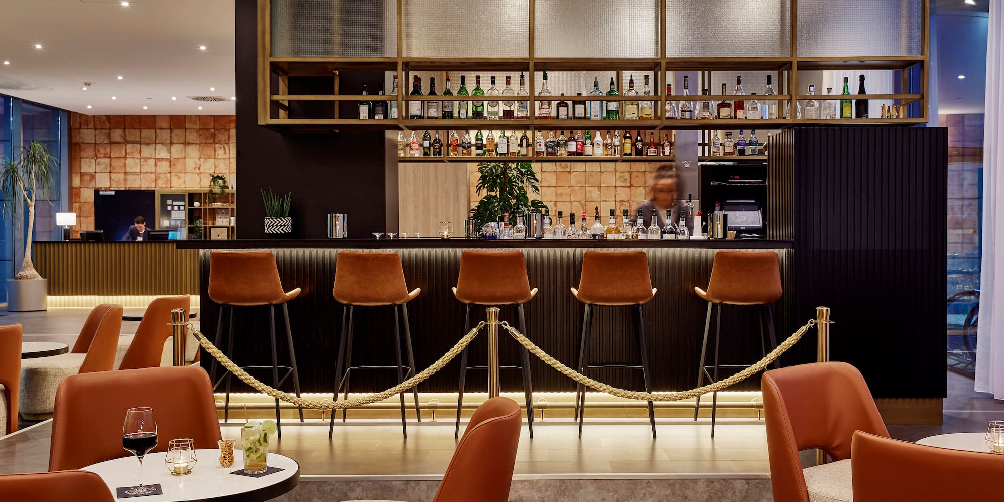 a bar with chairs and a bar with a man behind it