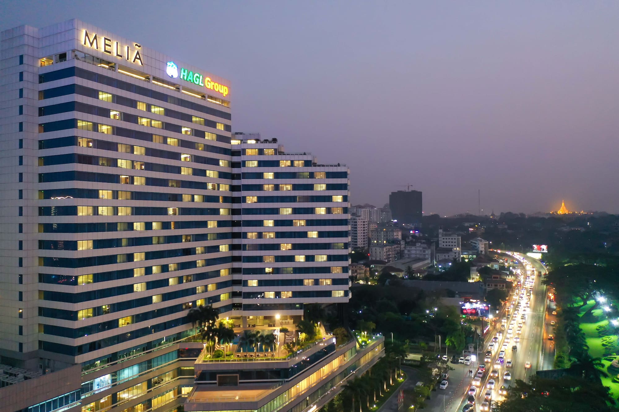 Meliá Yangon hotel at dusk, city traffic, distant Shwedagon Pagoda.