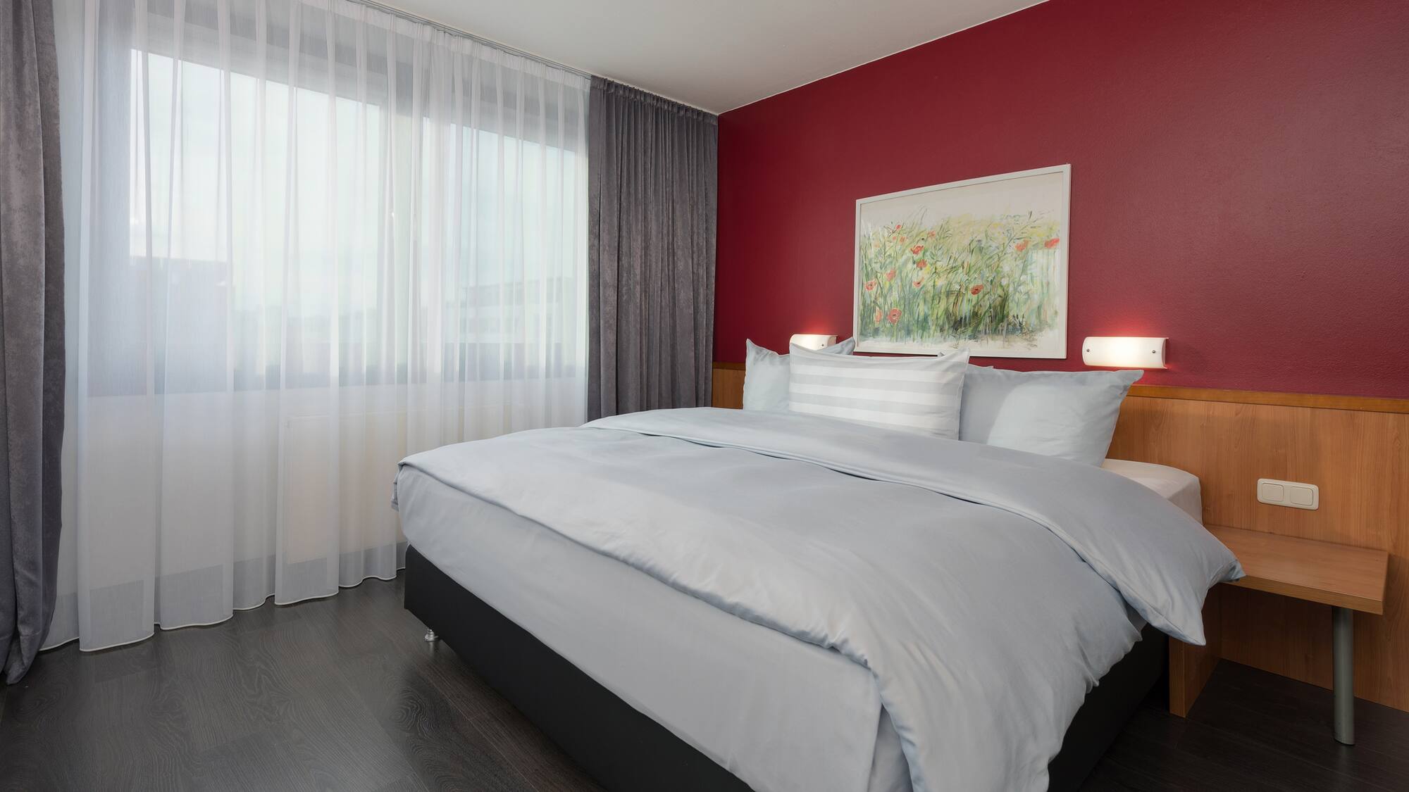 a bed with a red wall and white curtains