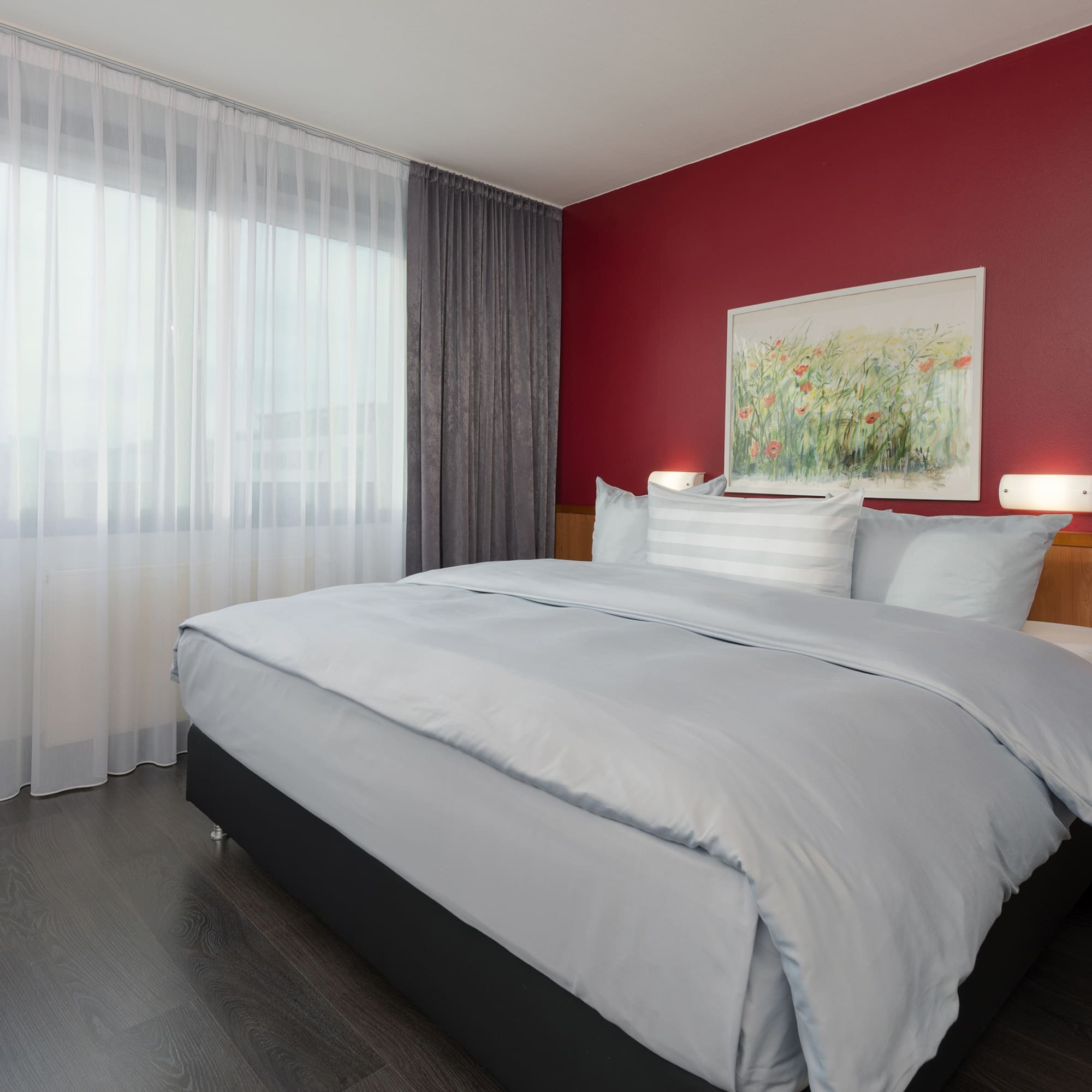 a bed with a red wall and white curtains
