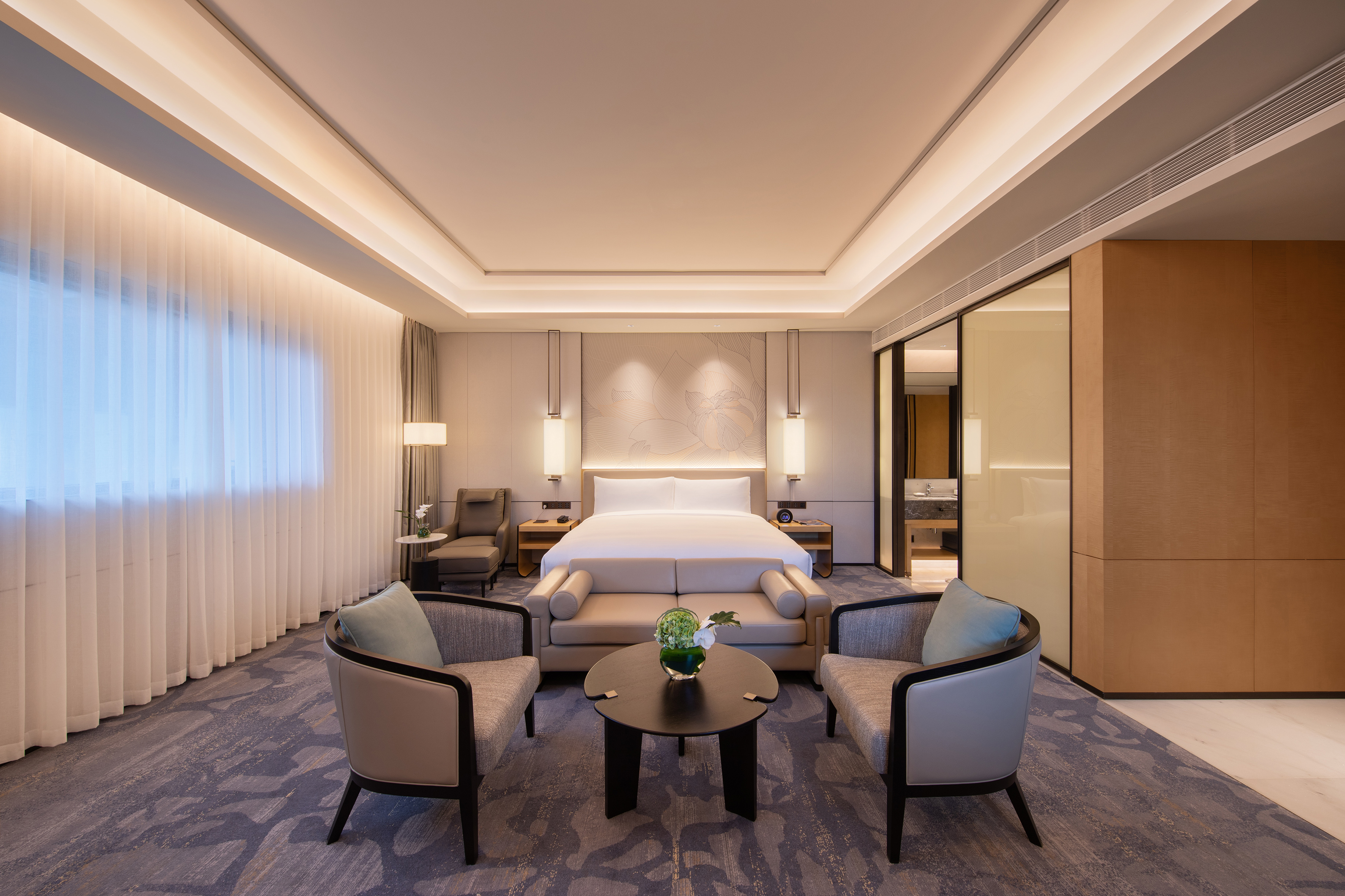 Elegant hotel suite featuring a king bed, seating area, and sleek modern design.