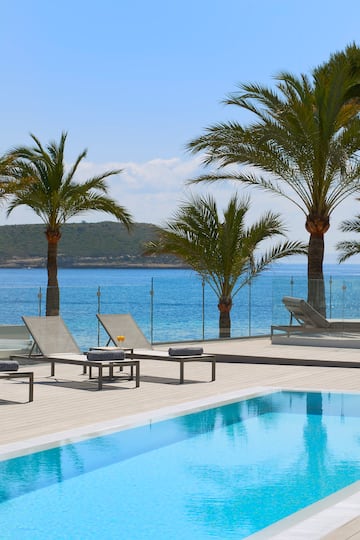 a pool with palm trees and chairs by the water