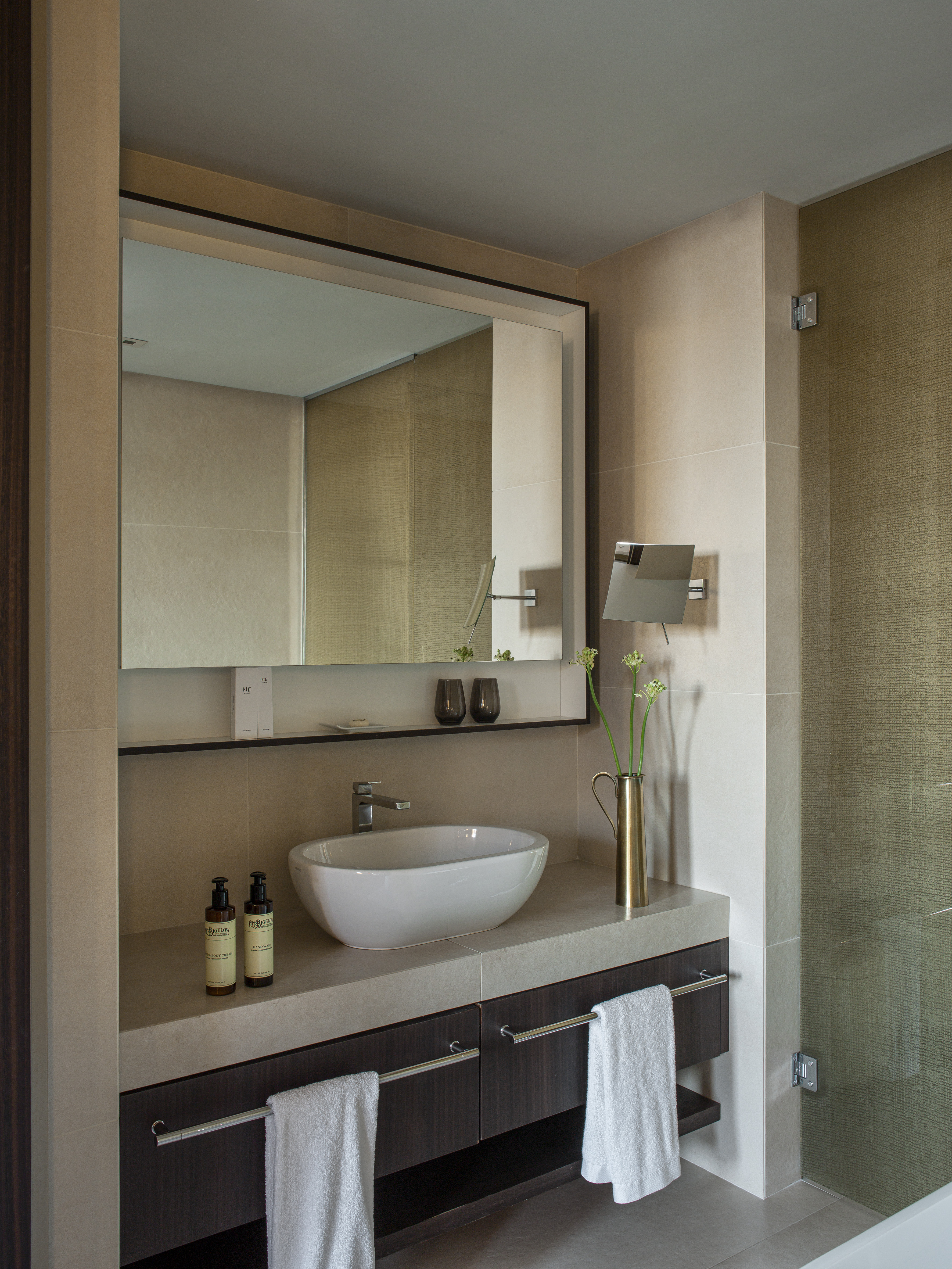Modern hotel bathroom vanity with vessel sink, concrete counter, dark wood, mirror.