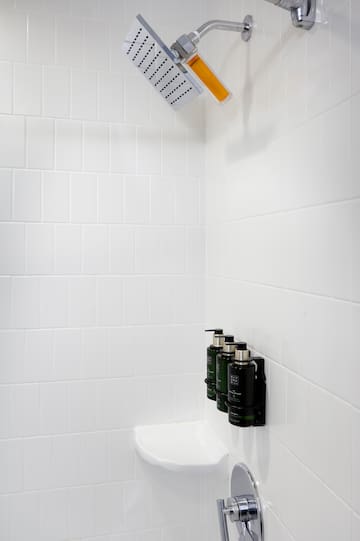 a shower with a shower head and soap dispensers