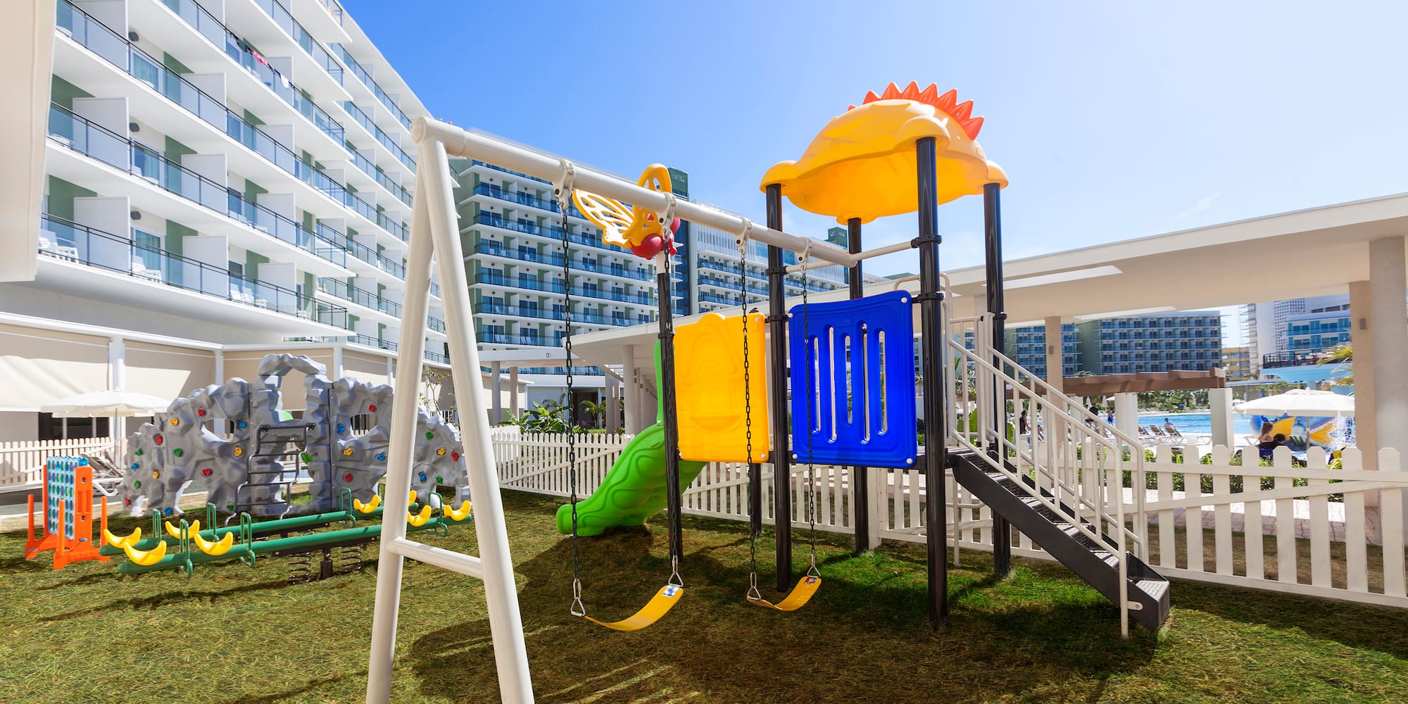 a playground with a slide and a white fence
