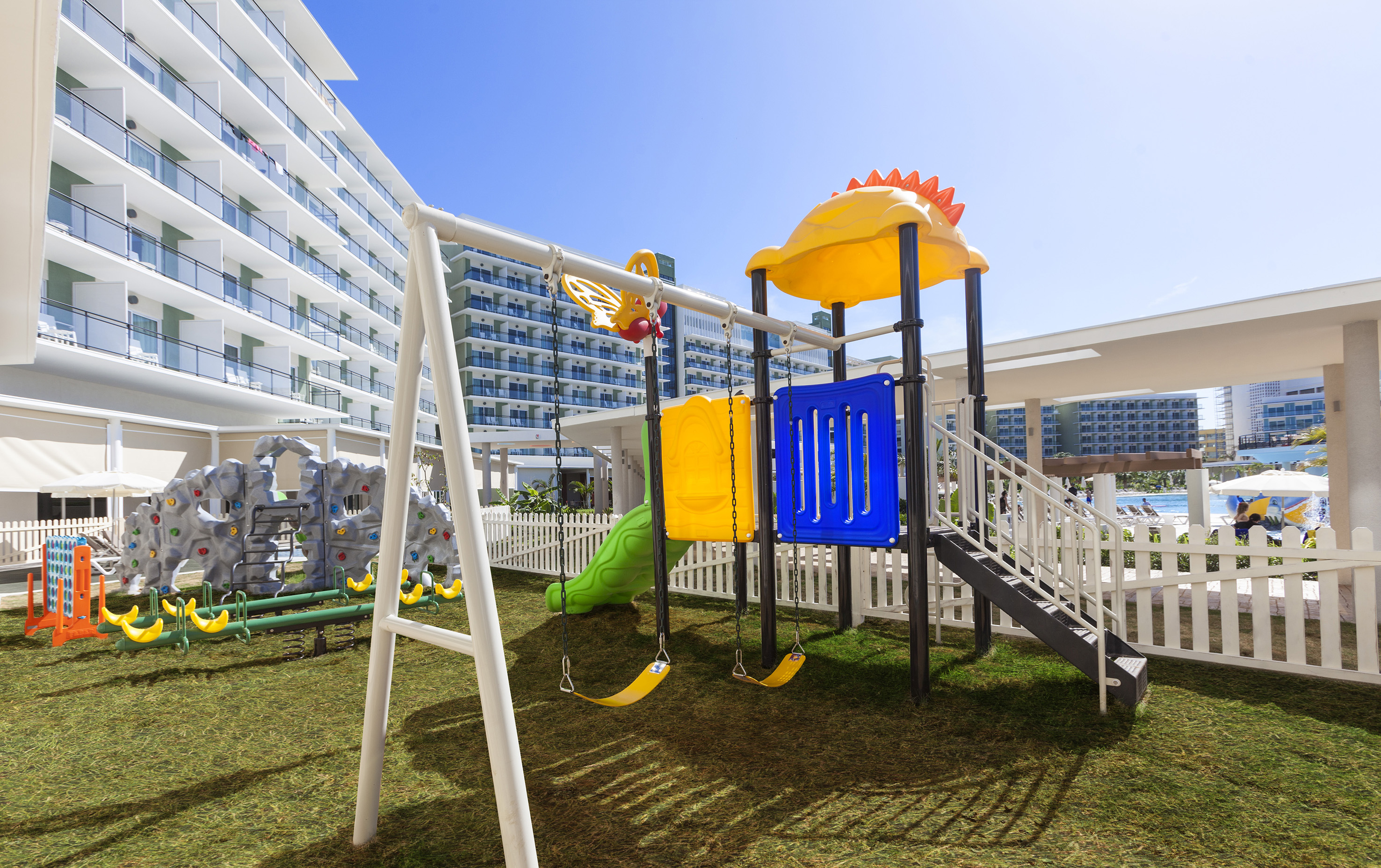 a playground with a slide and a white fence