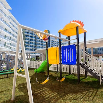 a playground with a slide and a white fence